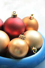 Image showing red and golden christmas ornaments in a blue bowl