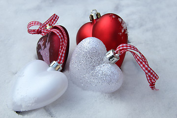 Image showing Red and white heart ornaments in snow