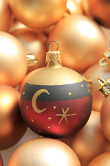 Image showing Red ornament on a pile of golden ornaments