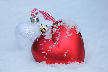 Image showing Red and white heart ornaments in snow