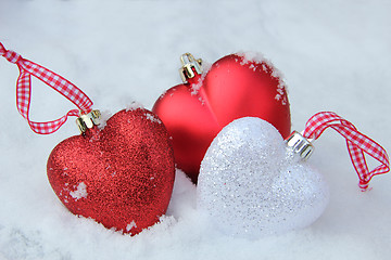 Image showing Red and white heart ornaments in snow