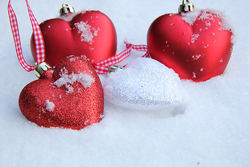 Image showing Red and white heart ornaments in snow