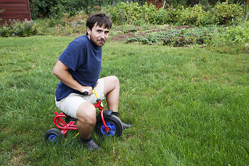 Image showing Adult man on a small tricycle