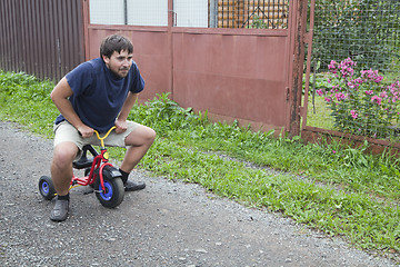 Image showing Adult man on a small tricycle