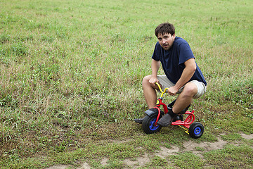 Image showing Adult man on a small tricycle