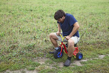 Image showing Adult man on a small tricycle