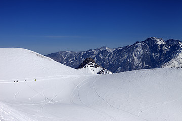 Image showing Snowboarders move on footpath to off piste slope at sun day