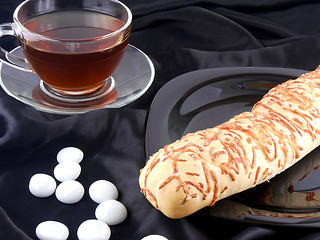 Image showing Hot tea with cheese bread and white stones on black background