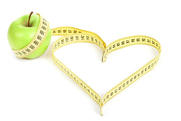 Image showing green apple with a measuring tape and heart symbol isolated