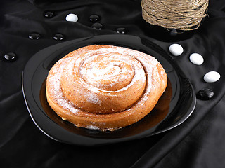 Image showing sweet cake on black background, white stones and wine bottle