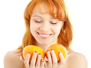 Image showing cheerful redhead holding two oranges over white