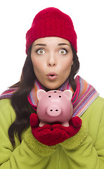 Image showing Expressive Mixed Race Woman Wearing Winter Hat Holding Piggybank