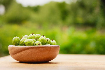 Image showing Close-Up Of Gooseberries In Vintage Wooden Bowl On Wooden Table