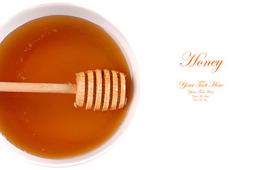 Image showing Closeup of a bowl of amber honey with a honey wand isolated on w