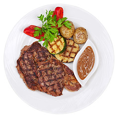 Image showing Grilled steaks, baked potatoes and vegetables on white plate on 