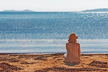 Image showing Portrait of young woman on the beach near the sea sitting wearin