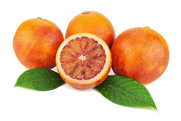 Image showing Ripe red blood oranges with cut and green leaves isolated on whi