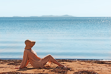 Image showing Portrait of young woman on the beach near the sea sitting wearin