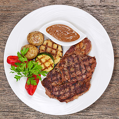 Image showing Grilled steaks, baked potatoes and vegetables on white plate on 