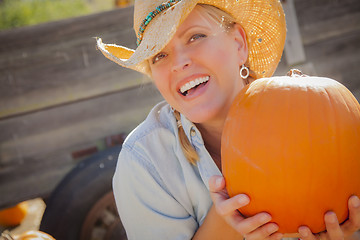 Image showing Beautiful Blond Female Rancher Wearing Cowboy Hat Holds a Pumpki