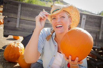 Image showing Beautiful Blond Female Rancher Wearing Cowboy Hat Holds a Pumpki