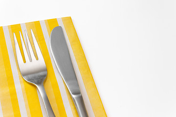 Image showing Fork and knife on a yellow napkin