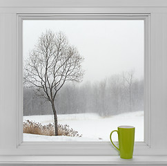 Image showing Winter landscape seen through the window and green cup