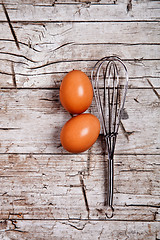 Image showing wire whisk and two brown eggs