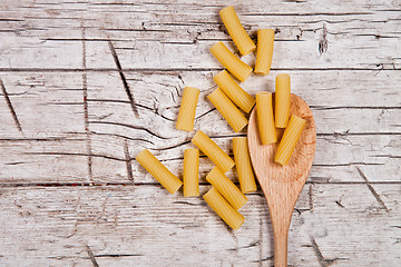 Image showing raw macaroni and wooden spoon 