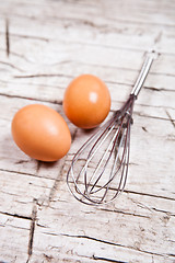 Image showing wire whisk and two brown eggs 