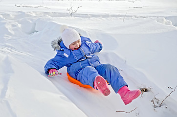 Image showing Little girl on a sled sliding on snow