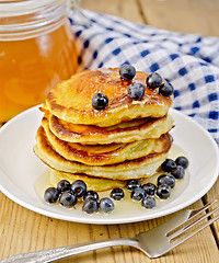 Image showing Flapjacks with blueberries and a jar of honey on the board