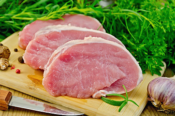Image showing Meat pork slices on a board with greens