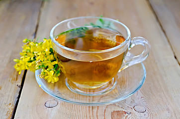 Image showing Herbal tea from tutsan in a glass cup on a board