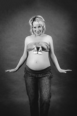 Image showing beautiful pregnant woman with child boots on her tummy