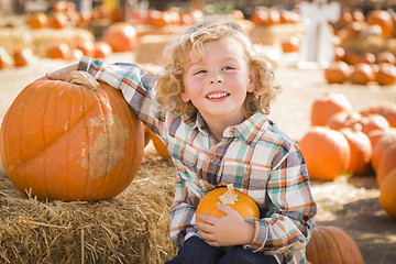 Image showing Little Boy Sitting and Holding His Pumpkin at Pumpkin Patch
