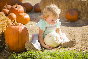 Image showing Adorable Baby Girl Holding a Pumpkin at the Pumpkin Patch
