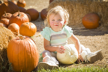 Image showing Adorable Baby Girl Holding a Pumpkin at the Pumpkin Patch
