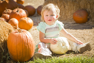 Image showing Adorable Baby Girl Holding a Pumpkin at the Pumpkin Patch
