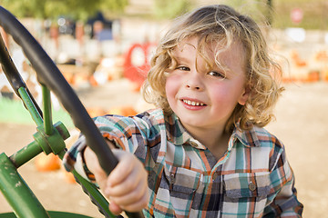 Image showing Adorable Young Boy Playing on an Old Tractor Outside