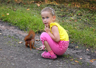 Image showing little girl feeding squirrel with nuts