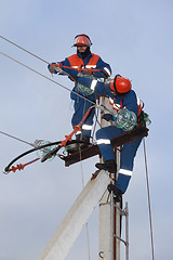 Image showing Two electrics working on top of an electricity pylon