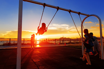 Image showing child playing swing against sunset