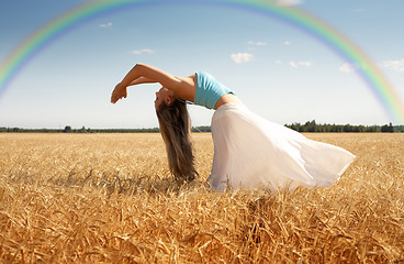 Image showing stretching woman in the meadow with rainbow