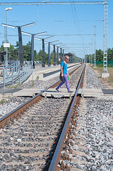 Image showing Man walking across the railroad tracks