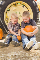 Image showing Two Boys Holding Pumpkins Talking and Sitting Against Tractor Ti