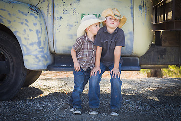 Image showing Two Young Boys Wearing Cowboy Hats Leaning Against Antique Truck