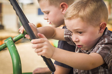 Image showing Adorable Young Boys Playing on an Old Tractor Outside