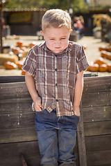 Image showing Frustrated Boy at Pumpkin Patch Farm Standing Against Wood Wagon