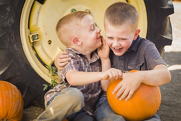 Image showing Two Boys Sitting Against Tractor Tire Holding Pumpkins Whisperin